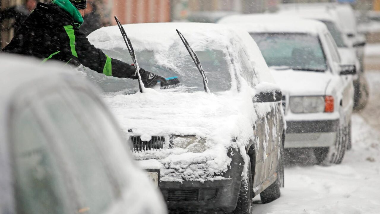 Čovek čisti auto od snega