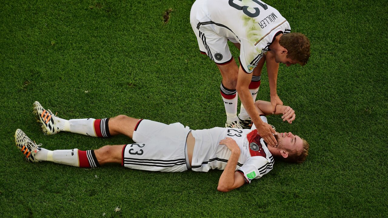 Tomas Miler pokušava da pomogne Krsitofu Krameru posle udarca u glavu koji je dobio u finalu SP protiv Argentine