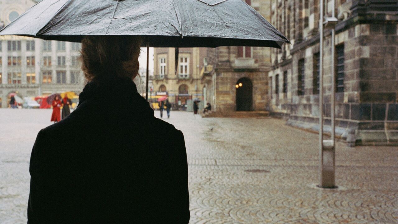 čovek na ulici stoji sa kišobranom