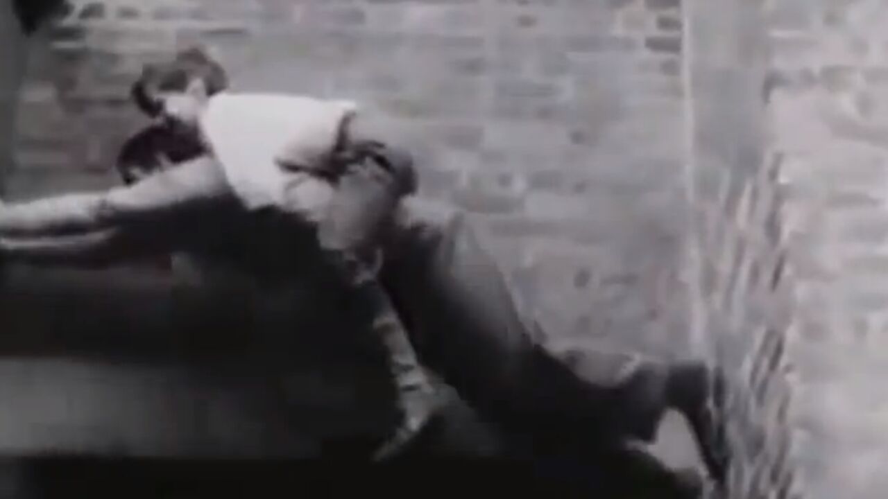 Moma se pentra po zgradama dok mu je dete na leđima