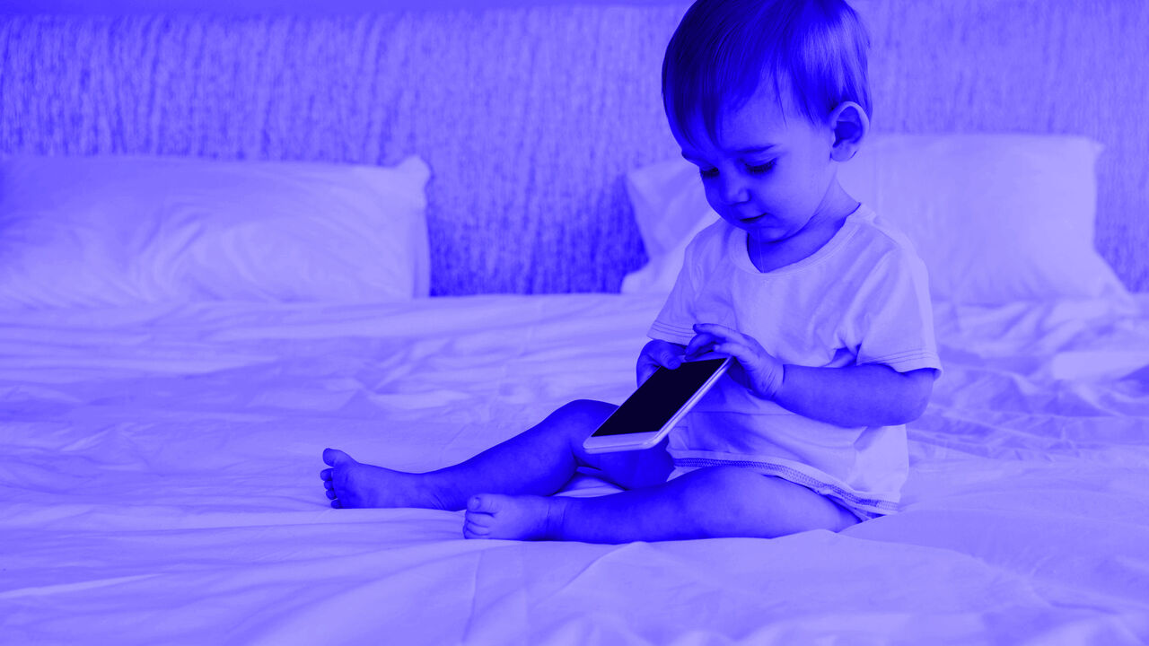 Dete u krevetu sa mobilnim telefonom